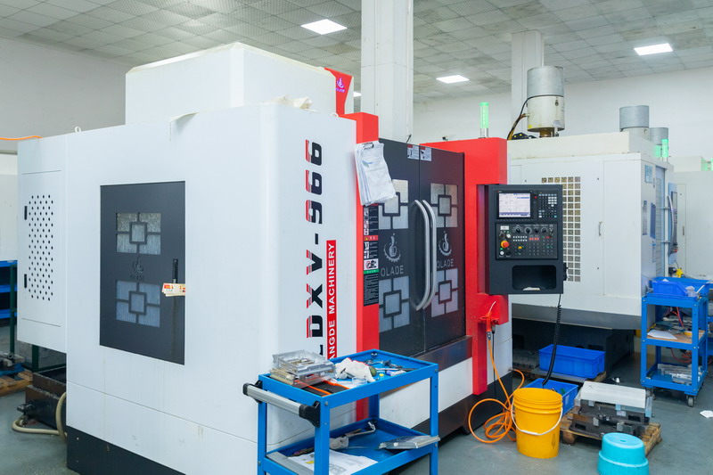 Two Oulangde enclosed vertical machining centres with tool trolley and parts bins in a workshop