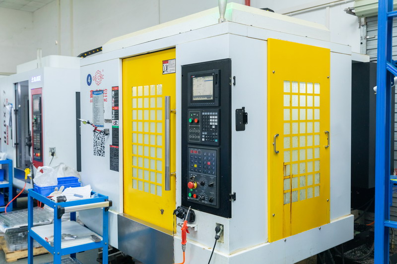 White enclosed vertical CNC machining centre with bright yellow doors and black control panel